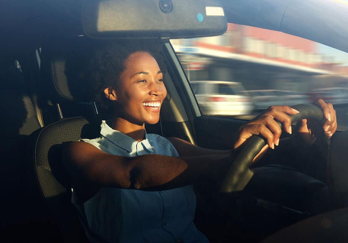 Happy woman driving a car with big smile.