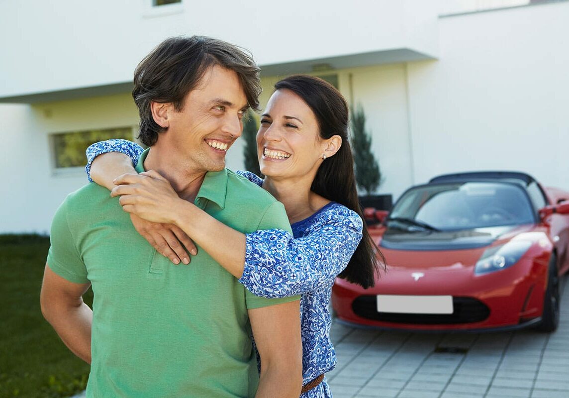Happy man and woman embracing in front of their car